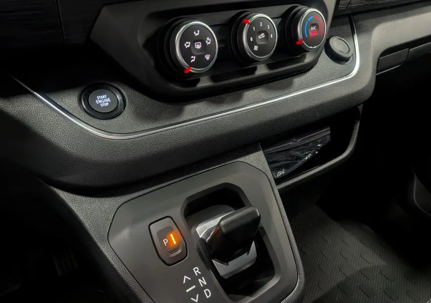 Gros plan sur la console centrale du Renault Trafic Combi gris comète, montrant la boîte auto et les commandes de climatisation.