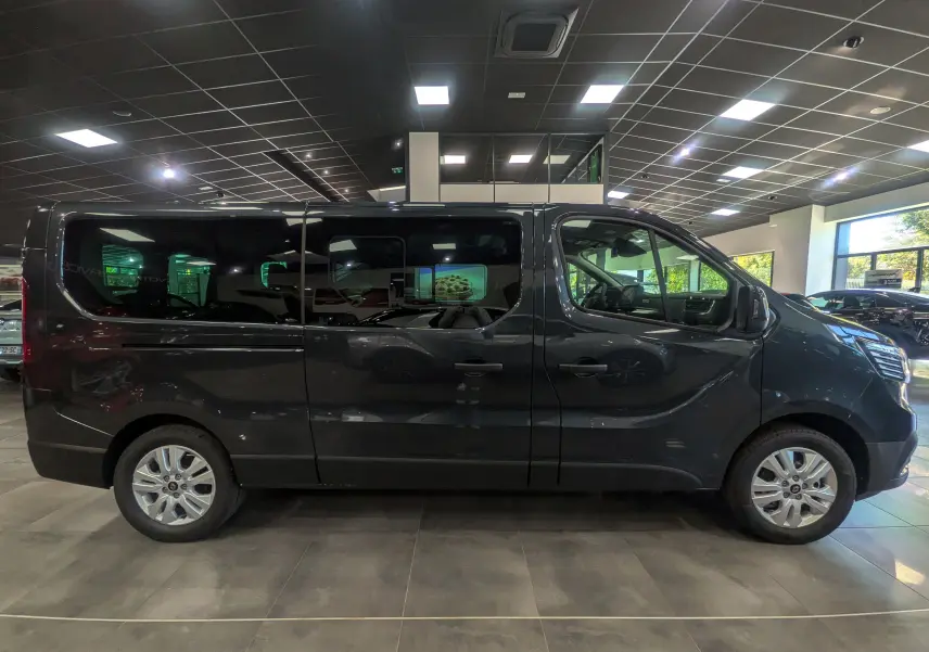 Profil droit d'un Renault Trafic Combi gris comète 2025 en intérieur, avec vitres teintées et jantes alliage.