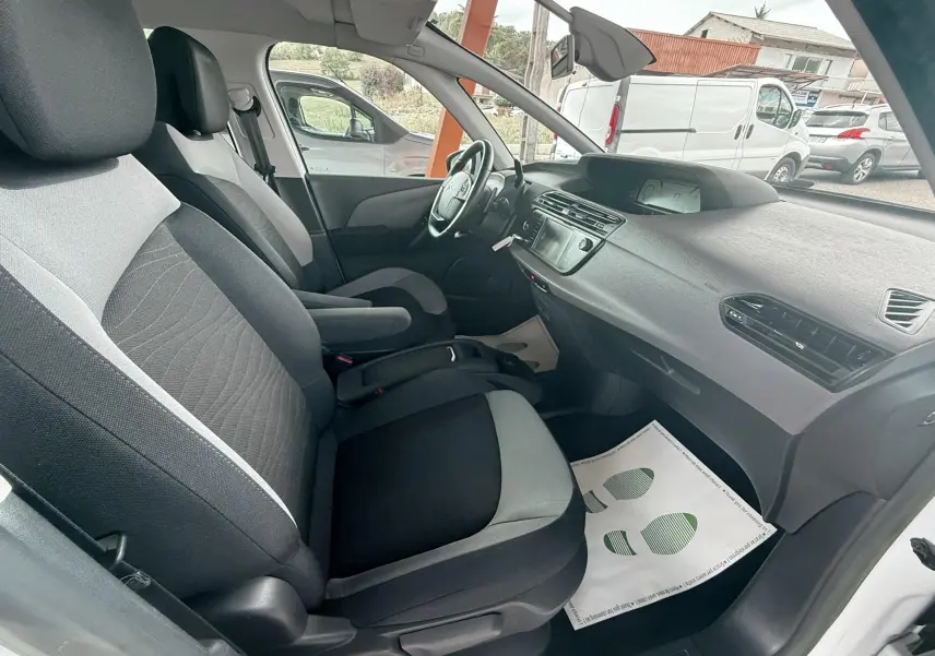 Intérieur avant droit d'une Citroën C4 Picasso blanc 2014, sièges tissu bicolore et tableau de bord moderne.