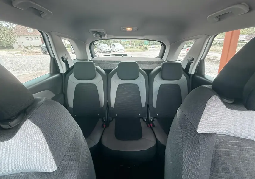 Vue intérieure arrière du Citroën C4 Picasso 2014 blanc, montrant les trois sièges arrière en tissu bicolore gris et noir.