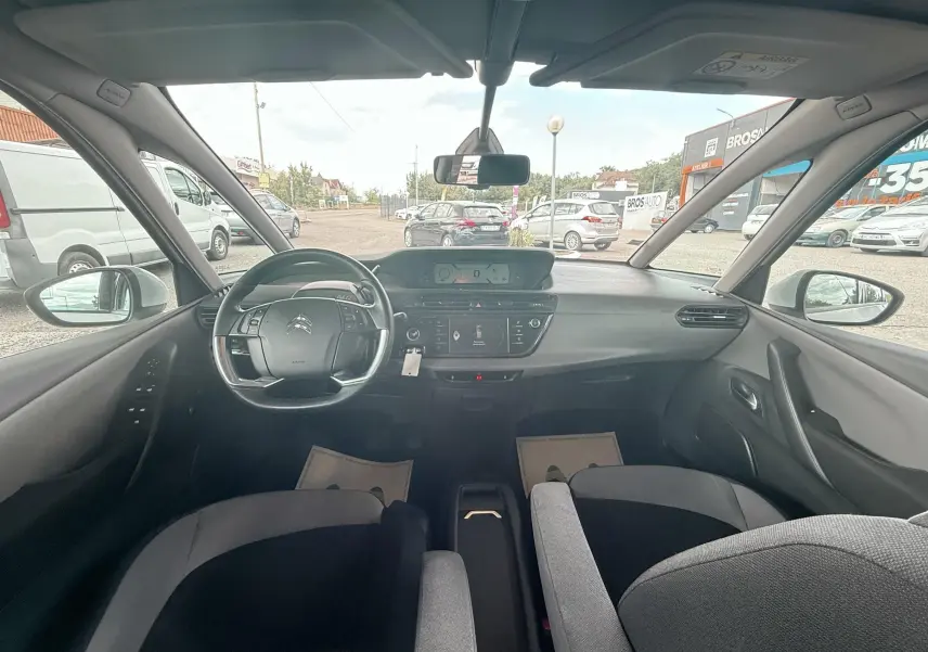 Vue intérieure avant du Citroën C4 Picasso blanc 2014, montrant le tableau de bord et le volant multifonction.