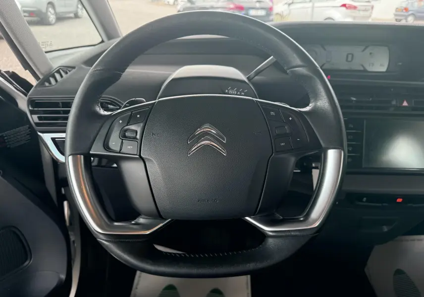 Vue rapprochée du volant cuir noir de la Citroën C4 Picasso 2014 avec commandes intégrées et tableau de bord numérique.