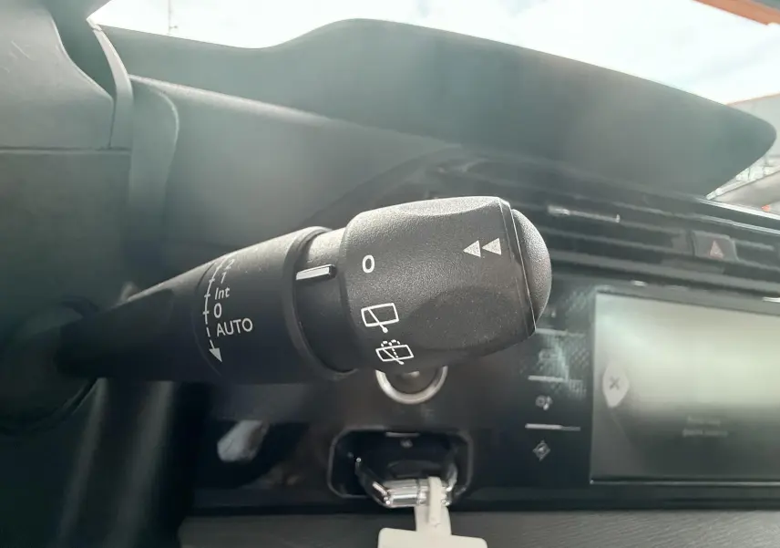 Gros plan sur la commande d’essuie-glace à gauche du tableau de bord du Citroën C4 Picasso blanc de 2014.