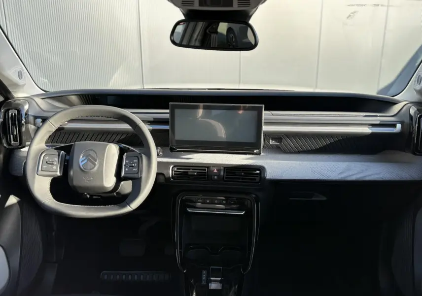 Vue intérieure avant du tableau de bord gris et noir du Citroën C3 Aircross Hybrid avec écran tactile central et volant multifonctions.