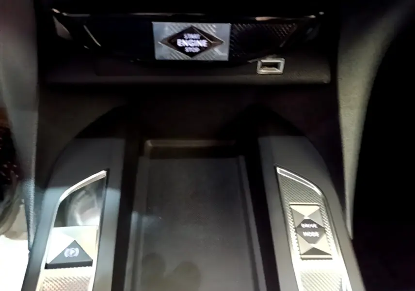 Gros plan sur la console centrale noire du DS3 Crossback avec boutons frein électrique et mode de conduite.