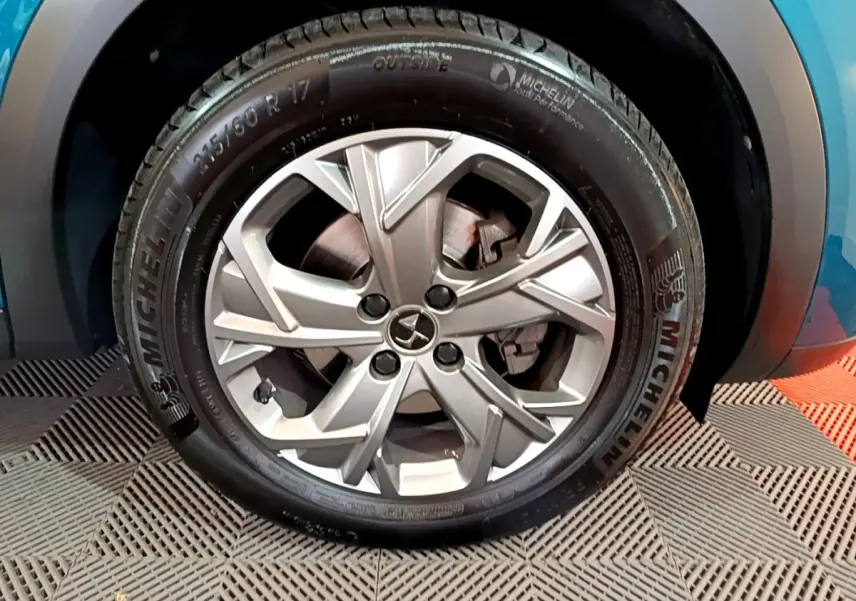 Gros plan sur la roue avant droite avec jante alliage argentée du DS3 Crossback bleu visible en arrière-plan.