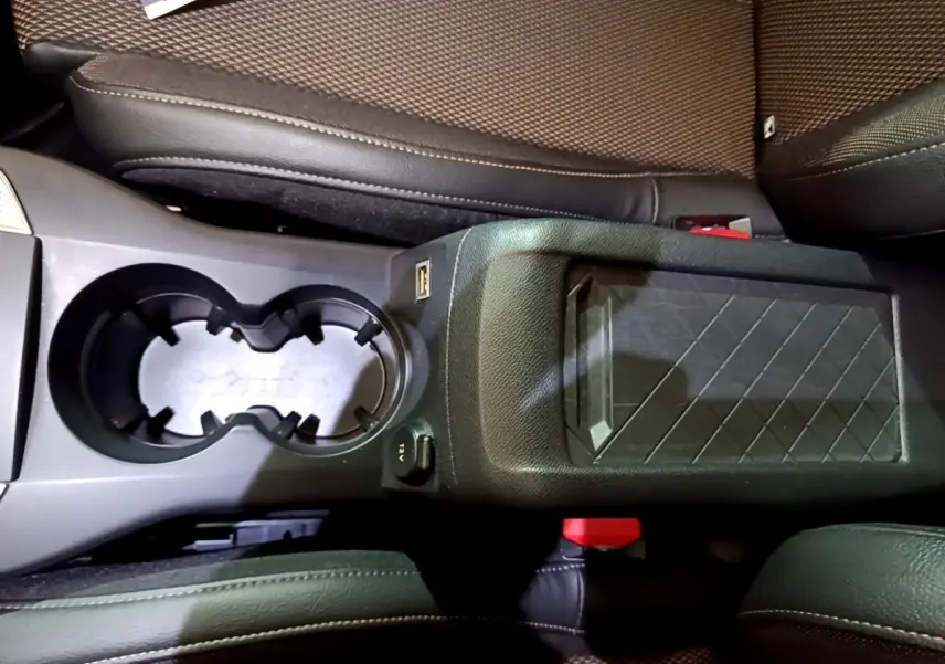 Vue plongeante sur la console centrale noire du DS3 Crossback bleu, avec porte-gobelets et accoudoir à motif géométrique.