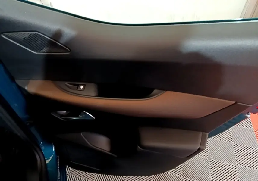 Vue rapprochée de la porte avant gauche du DS3 Crossback bleu, montrant la poignée et les commandes de fenêtre.