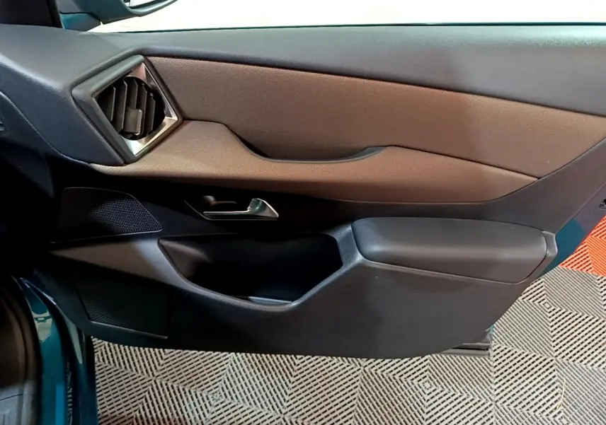 Intérieur côté gauche de la porte d’une DS3 Crossback bleu 2020, avec garniture marron et noire et poignée argentée.