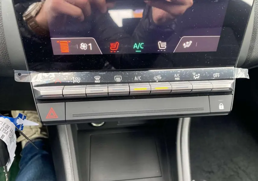 Vue rapprochée de la console centrale du Renault Captur 2025 avec commandes climatisation et sièges chauffants allumés.