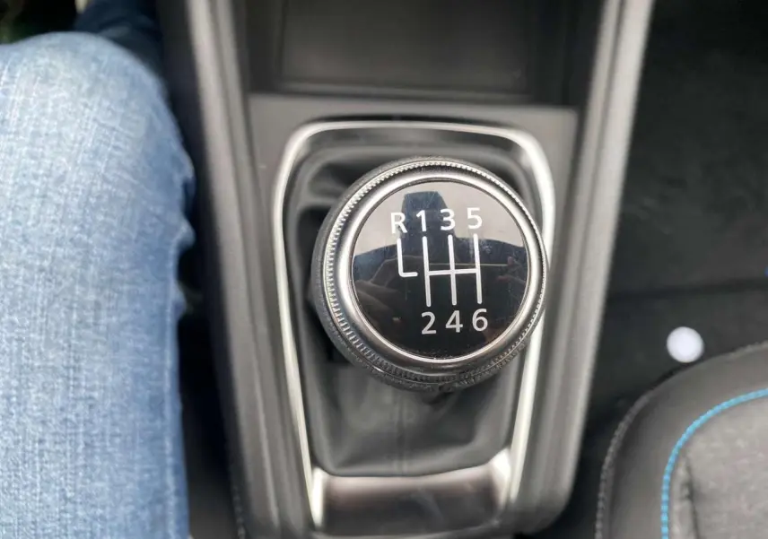Gros plan sur le levier de vitesses manuel du Renault Captur noir étoilé, avec couture bleue visible sur le siège adjacent.