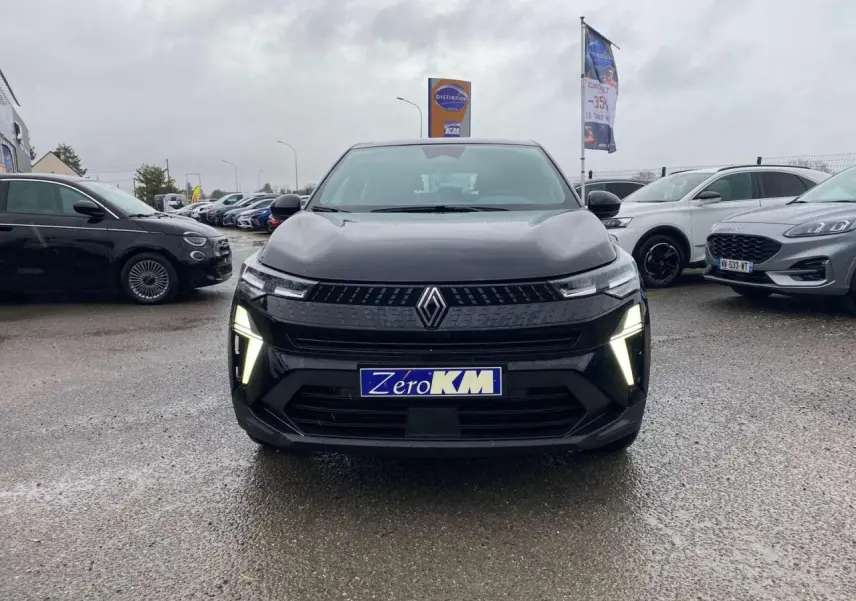 Vue de face du Renault Captur 2025 noir étoilé avec feux LED allumés sur parking humide.