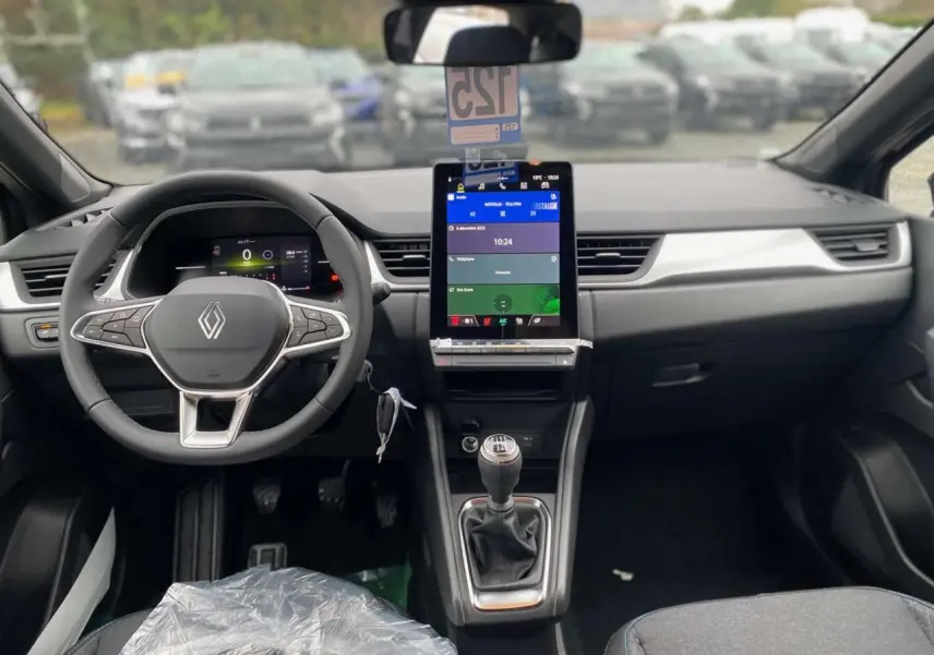 Vue intérieure frontale du Renault Captur 2025 avec volant, écran tactile vertical et levier de vitesses manuel visible.
