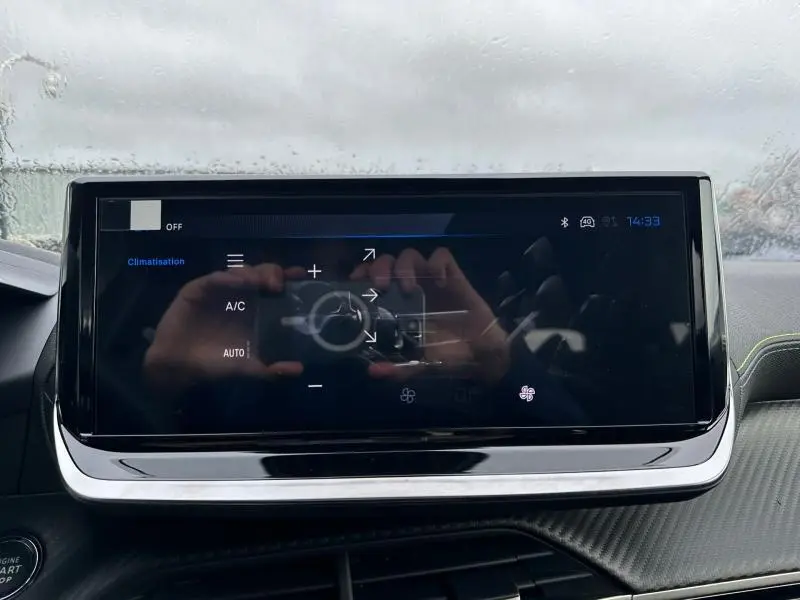 Écran tactile central du tableau de bord du Peugeot 2008 gris 1.2 Hybrid 145ch GT, affichant les commandes de climatisation.