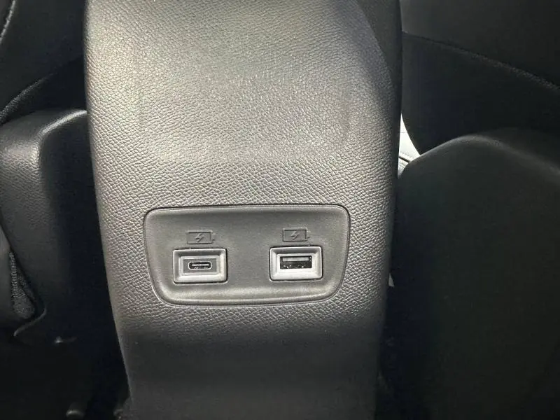 Vue rapprochée des ports USB de recharge situés à l'arrière de la console centrale d'un Peugeot 2008 gris hybride 2025.
