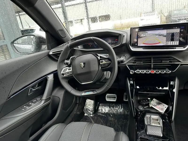 Vue intérieure avant de la Peugeot 2008 gris 2025, avec volant compact, écran tactile et affichage caméra de recul.