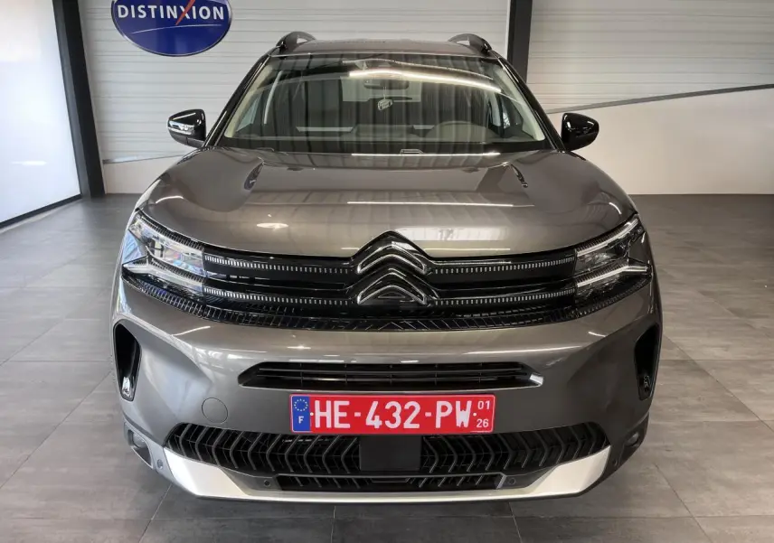 Vue frontale d'un Citroën C5 Aircross gris platinium avec calandre noire brillante et plaques rouges d'essai.