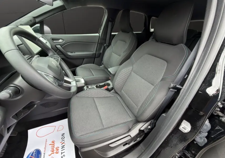 Vue intérieure côté conducteur du Renault Symbioz noir 2025, montrant les sièges avant en tissu gris et le volant multifonctions.