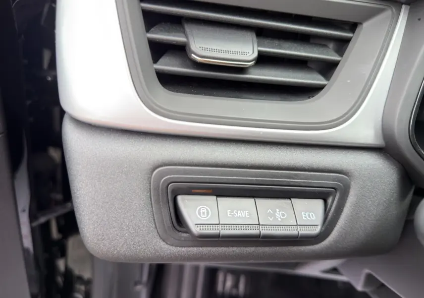 Gros plan sur les commandes E-SAVE, réglage phares et mode ECO sous la sortie d'air côté conducteur du Renault Symbioz noir.