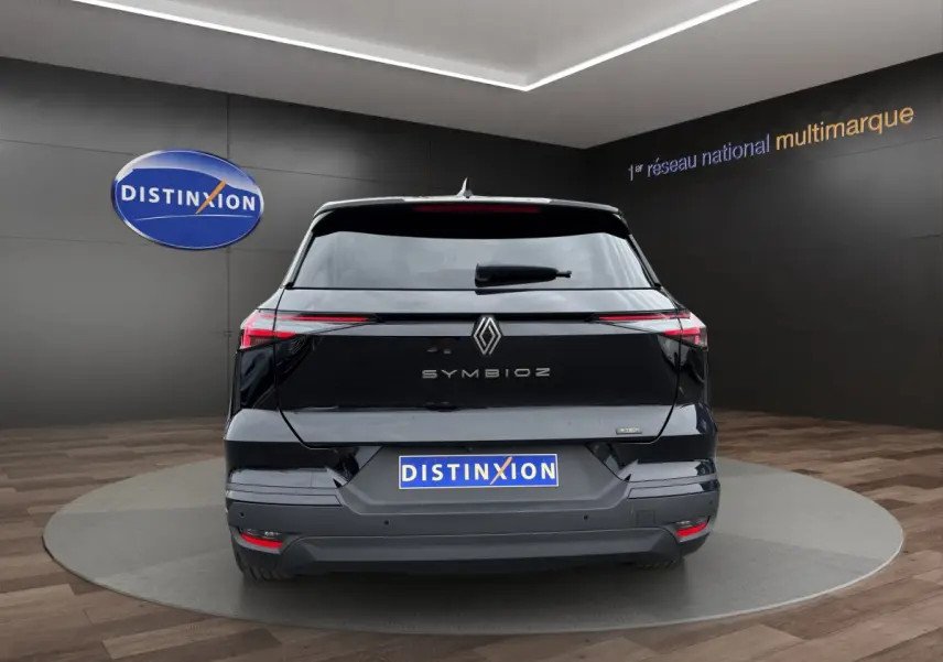 Vue arrière d'une Renault SYMBIOZ noire 2025 avec feux LED fins et logo centré sur un fond intérieur showroom.