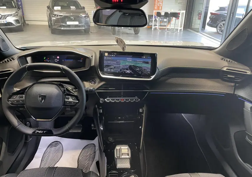 Vue intérieure avant du Peugeot 2008 blanc 2026, tableau de bord avec écran tactile et volant compact cuir noir.
