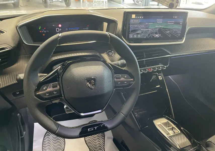 Vue intérieure du poste de conduite du Peugeot 2008 GT 2026, volant compact cuir et écran tactile 10 pouces avec navigation.