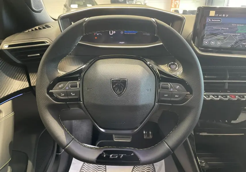 Vue intérieure centrée sur le volant cuir noir GT avec tableau de bord numérique et écran tactile Peugeot 2008 hybride.