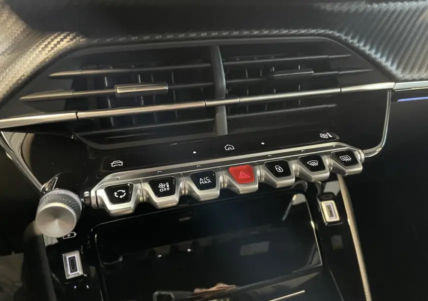 Vue rapprochée de la console centrale intérieure noire avec commandes et prises USB du Peugeot 2008 blanc hybride 2026.