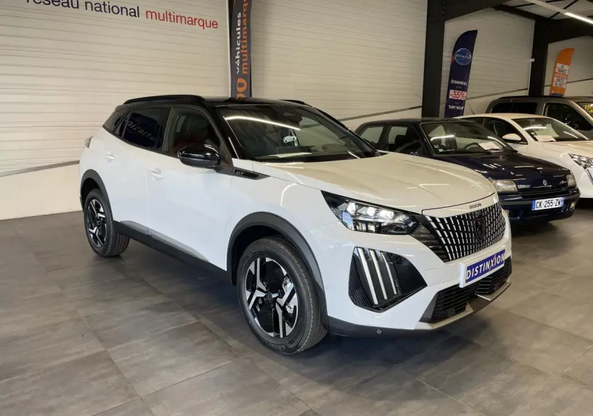Peugeot 2008 hybride blanche vue 3/4 avant droit en intérieur, toit noir et calandre à liserés chromés.