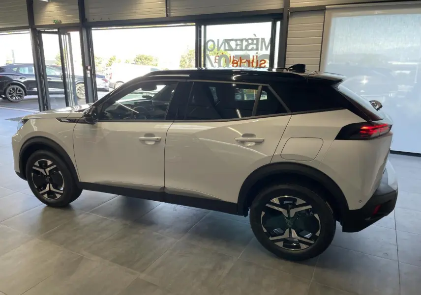 Peugeot 2008 blanc vue de profil côté gauche, toit noir et jantes alliage distinctives en concession.