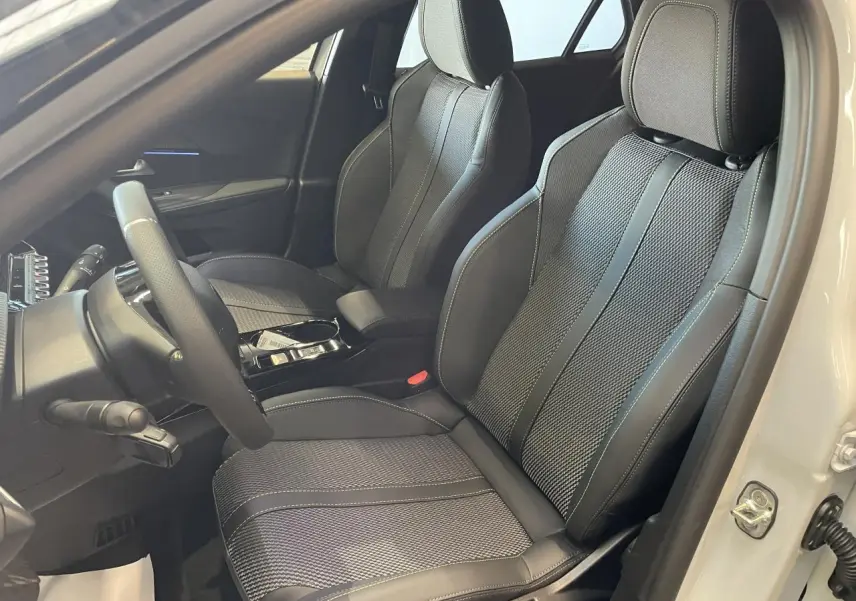 Vue intérieure côté conducteur du Peugeot 2008 blanc, mettant en valeur les sièges sport noirs avec surpiqûres claires.