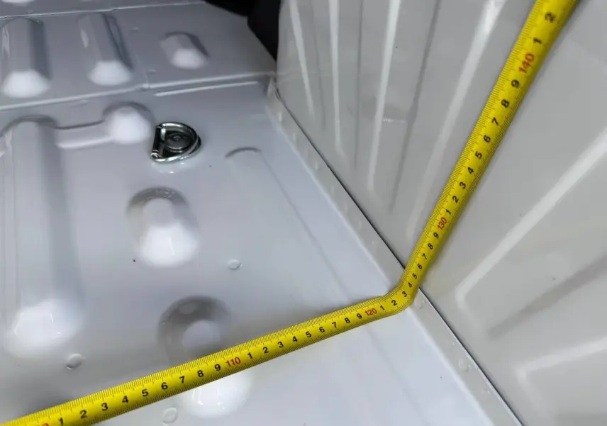 Détail de la zone de chargement blanche du Peugeot Partner 2026 avec mètre ruban jaune mesurant l'espace intérieur.