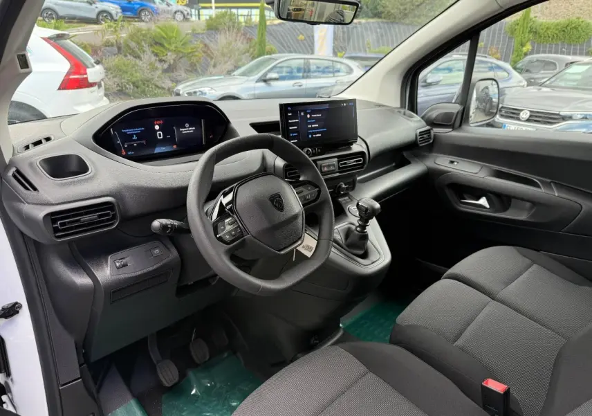 Vue intérieure côté conducteur du Peugeot Partner blanc Icy 2026, avec tableau de bord numérique et volant multifonction.