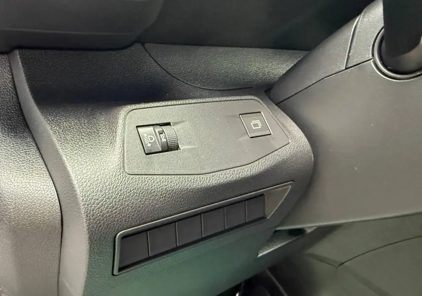 Gros plan sur les commandes de réglage des phares et de la fermeture de la porte côté conducteur du Peugeot Partner blanc Icy 2026.