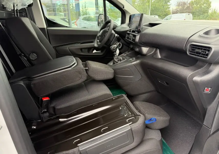 Vue intérieure côté conducteur du Peugeot Partner blanc Icy 2026, montrant les sièges et le tableau de bord noir.