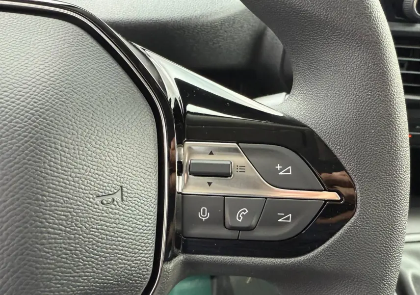Gros plan sur les commandes multifonctions noires du volant du Peugeot Partner blanc Icy, côté droit.
