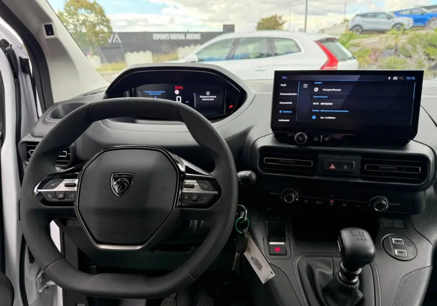 Vue intérieure du poste de conduite du Peugeot Partner blanc Icy 2026, volant multifonction et écran tactile central.