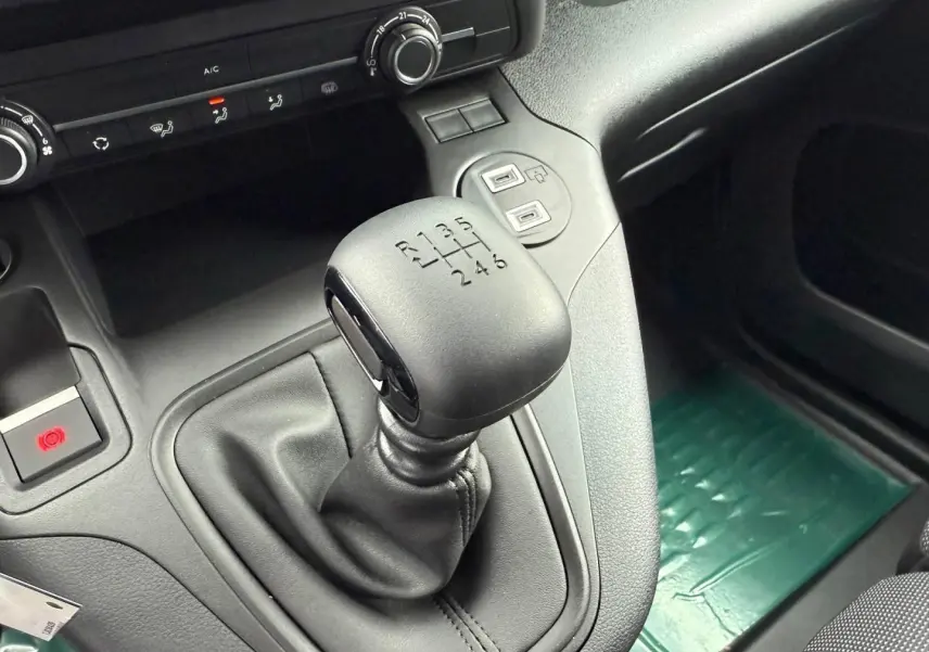 Gros plan sur le levier de vitesses manuel noir du Peugeot Partner 2026, avec console centrale et commandes clim visibles.
