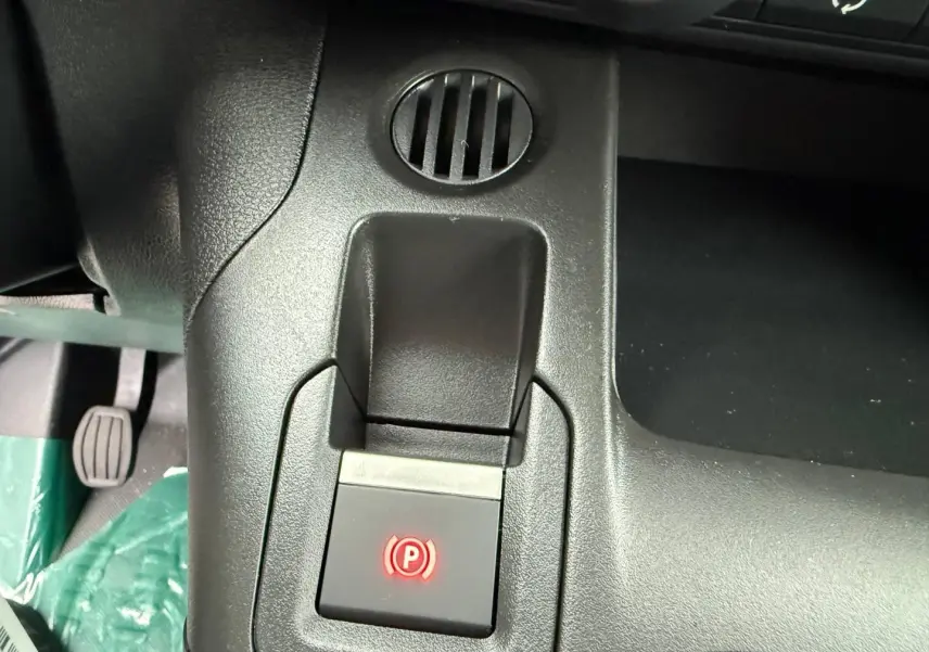 Gros plan sur la commande de frein à main électrique rouge dans l'habitacle du Peugeot Partner blanc Icy.