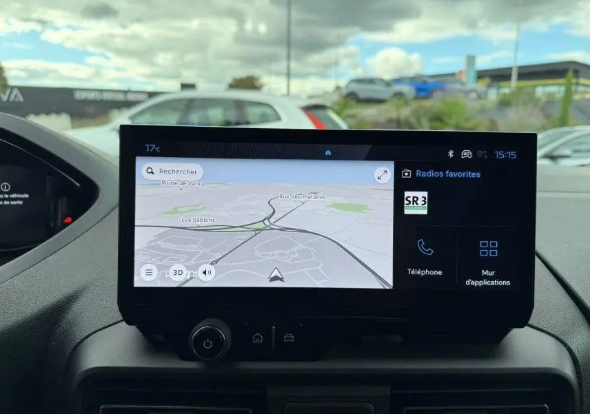 Écran tactile central affichant la navigation GPS et les radios favorites dans un Peugeot Partner blanc Icy, vue intérieure frontale.