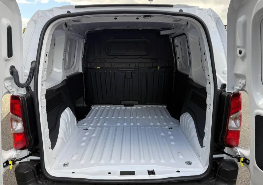 Vue arrière ouverte du Peugeot Partner blanc Icy 2026, montrant l'espace de chargement vide et la cloison noire intérieure.