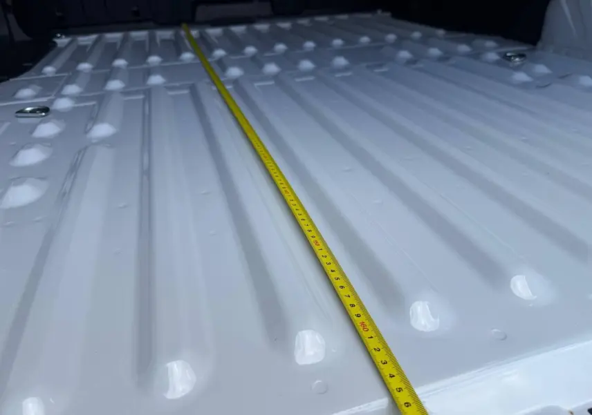 Gros plan sur la surface blanche Icy du plancher de chargement du Peugeot Partner avec un mètre ruban jaune posé dessus.