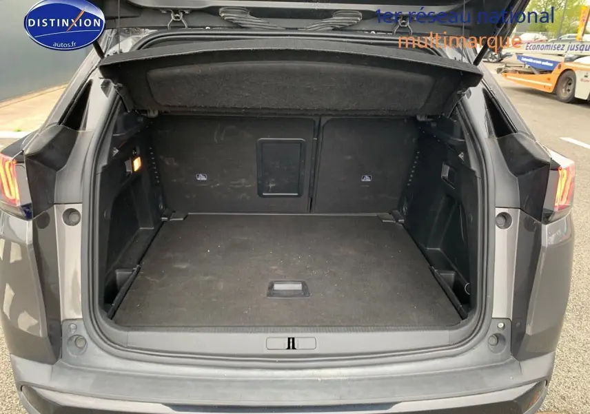 Coffre ouvert d'un Peugeot 3008 gris platinium metal vu de l'arrière, montrant un espace de chargement spacieux et propre.