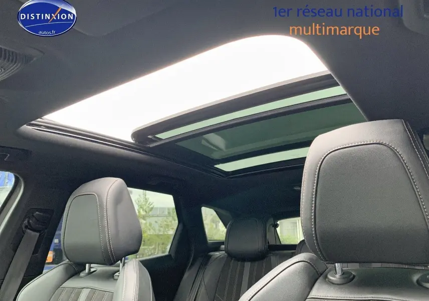 Vue intérieure du Peugeot 3008 gris platinium, montrant les sièges avant en cuir noir et le toit panoramique ouvert.