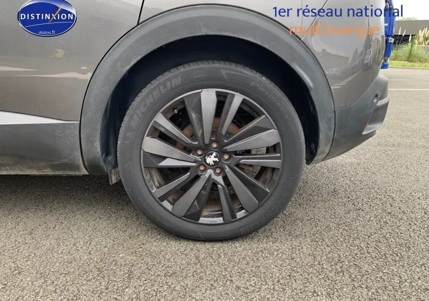 Gros plan sur la roue arrière droite du Peugeot 3008 gris platinium métal avec jante alliage sombre et logo lion central.