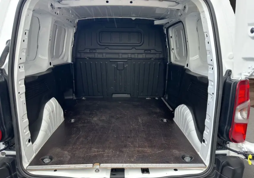 Vue arrière du Peugeot Partner blanc 2022, montrant l'espace de chargement vide avec parois blanches et plancher noir antidérapant.