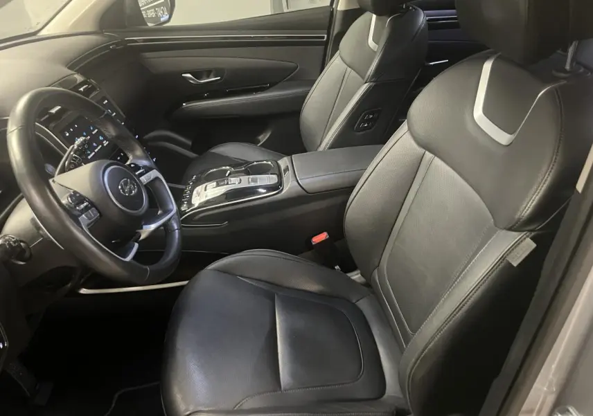 Vue intérieure côté conducteur du Hyundai Tucson 2023 avec sièges cuir noirs et console centrale moderne.
