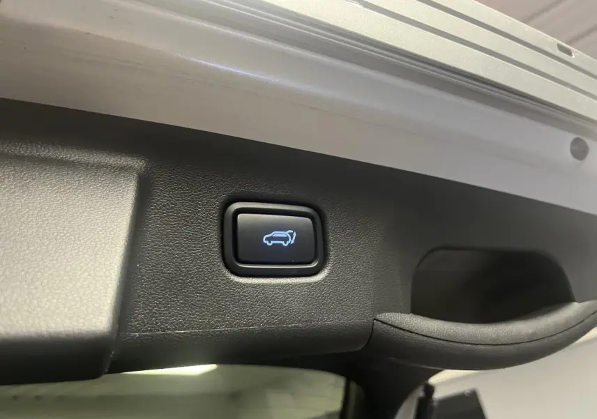 Bouton d'ouverture électrique du hayon sur le coffre d'un Hyundai Tucson gris 2023 hybride rechargeable.
