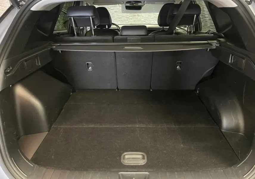 Coffre spacieux du Hyundai Tucson gris 2023 vu de l'arrière avec cache-bagages et sièges arrière rabattus.