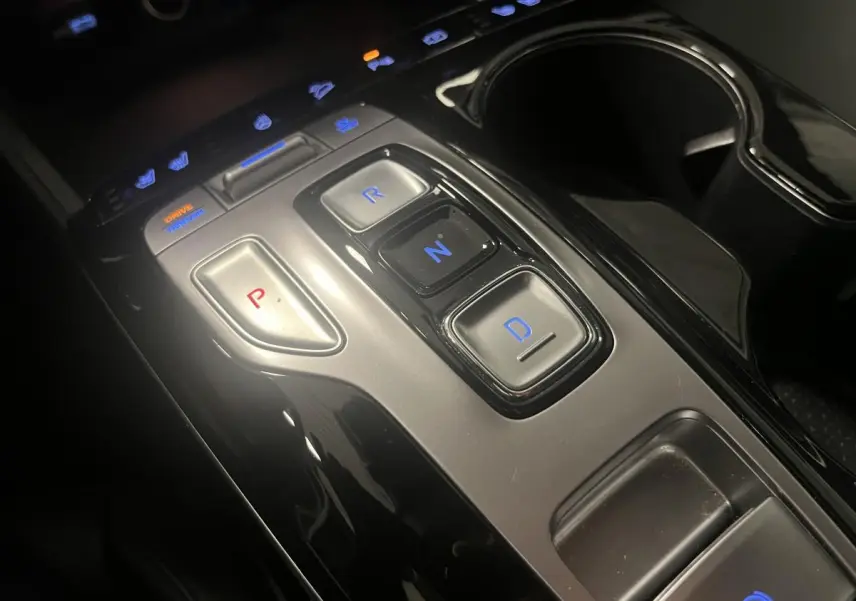 Gros plan sur la console centrale du Hyundai Tucson gris 2023, avec commandes de boîte automatique à boutons lumineux.